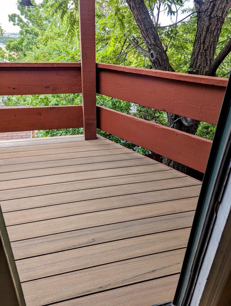 Wooden deck with brown railing, tree visible in the background.