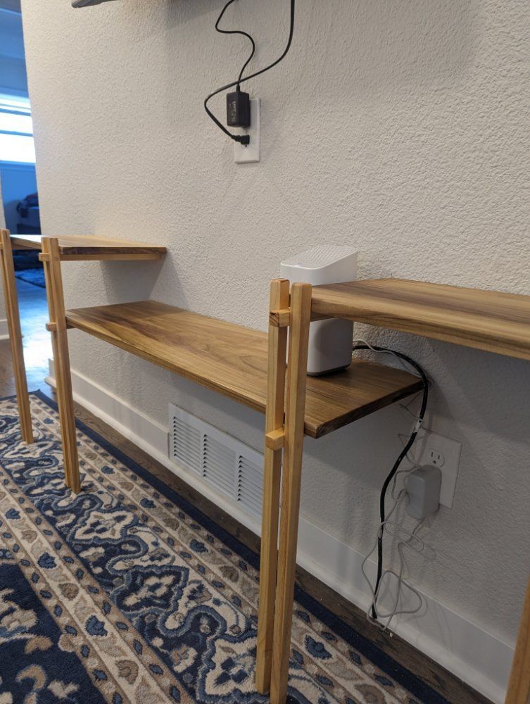 A person digs a trench in a backyard near a small excavator, a tree, and a house.