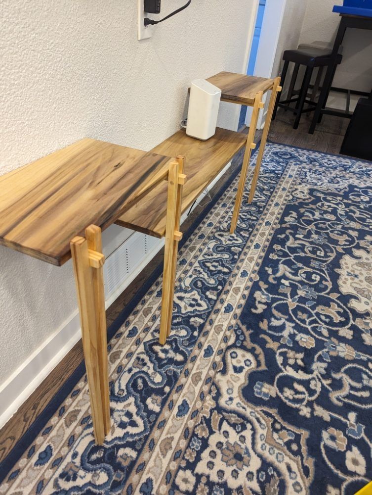 Wooden console table against a white wall, with a router on top. Blue patterned rug below.