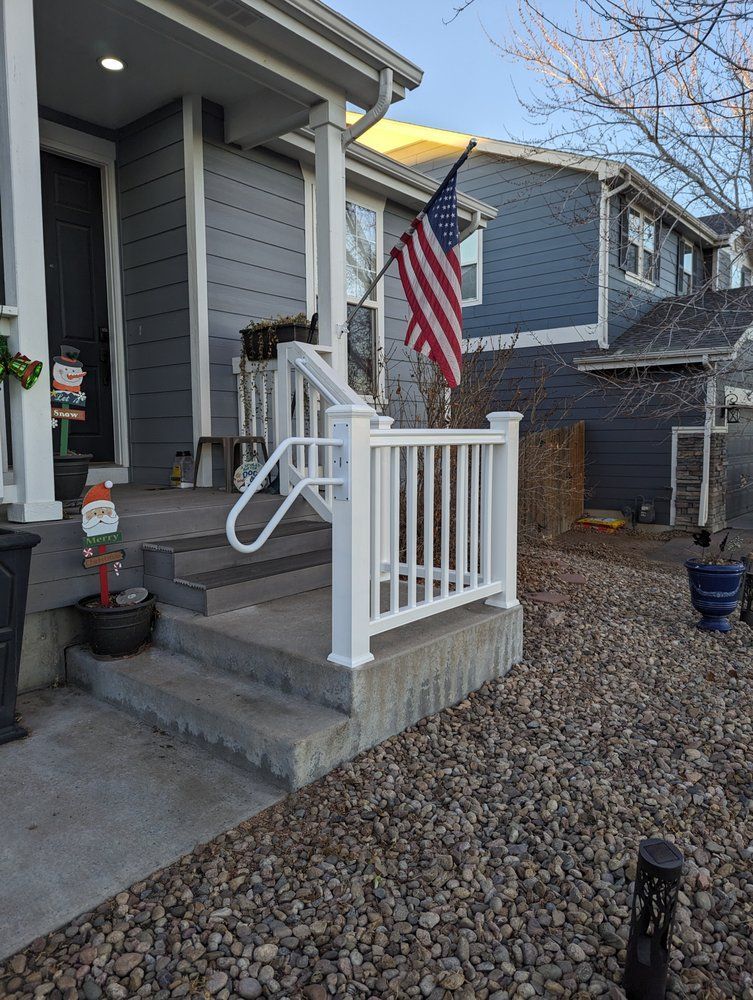 Front porch of a gray house with white railing and an American flag.