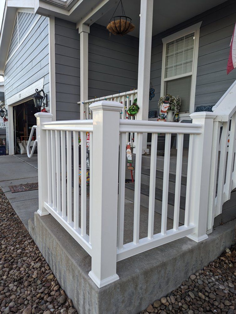White porch railing on a gray house with a small front porch and steps.