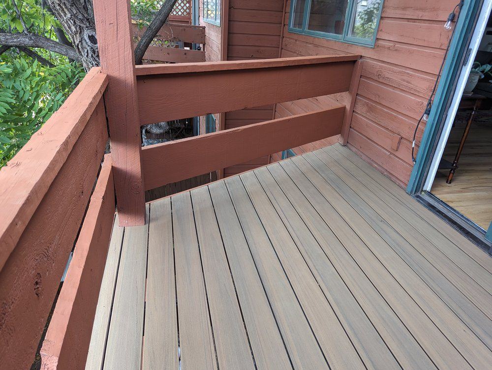 Deck with brown railings and grey wood planks. A glass door is to the right.