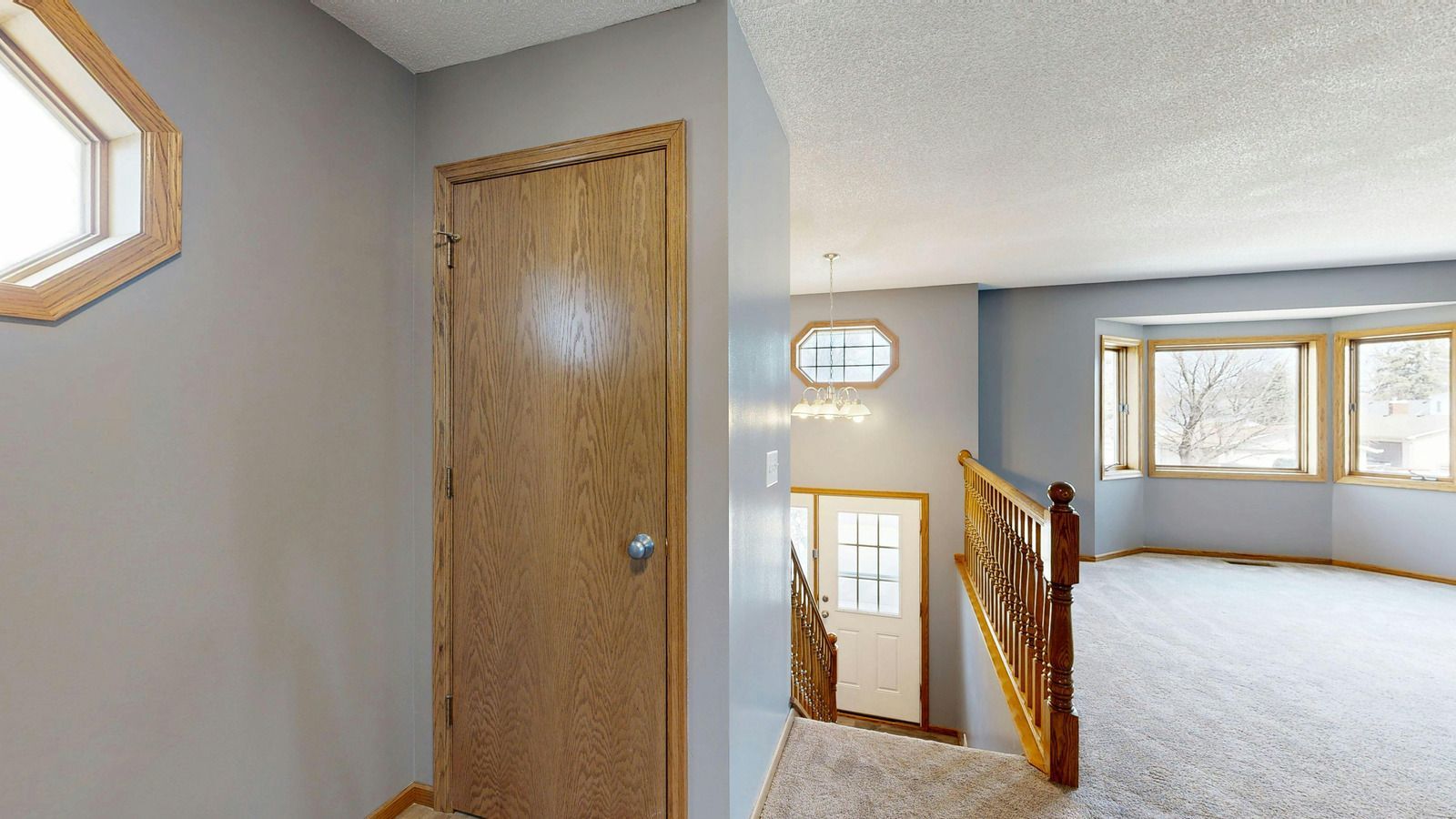 Wooden deck with brown railing, tree visible in the background.