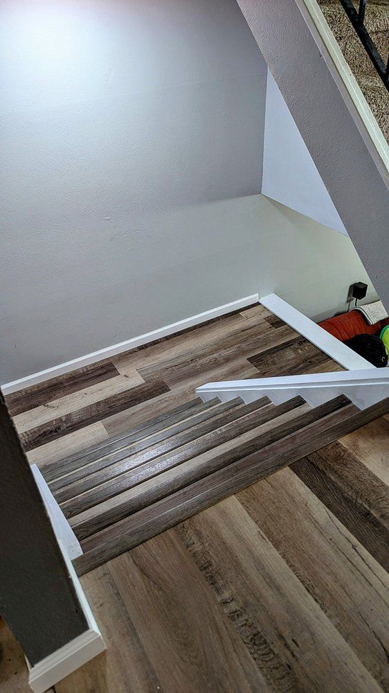 Staircase with wood-look flooring and white trim, leading downwards against gray walls.