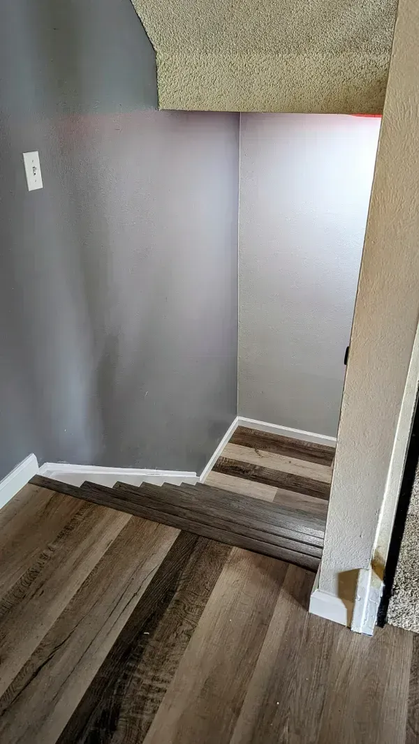 Staircase with wood-look flooring and steps. Gray walls, white trim. Top level carpeted.