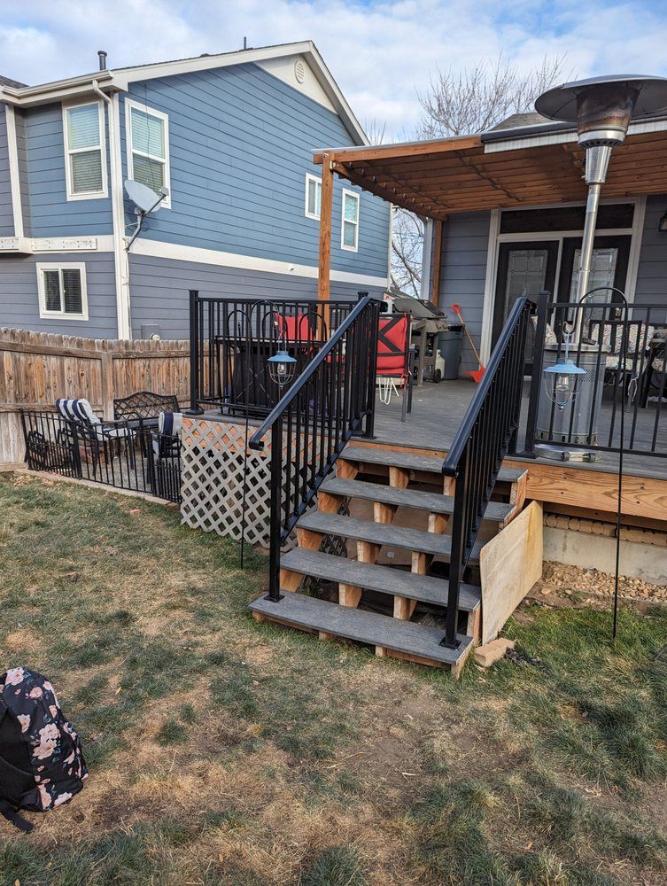 Living room with wood-look flooring, gray couch, plants, and stairs.
