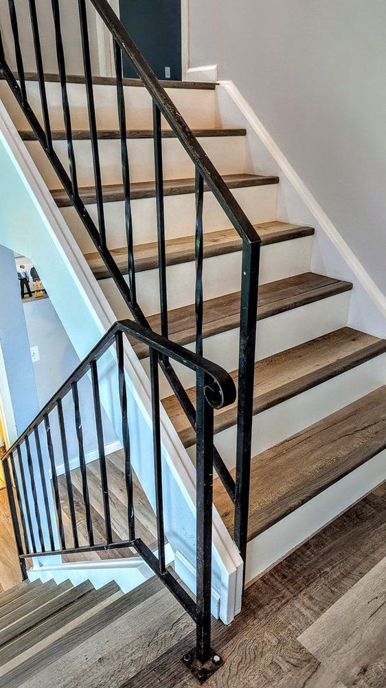 A person digs a trench in a backyard near a small excavator, a tree, and a house.