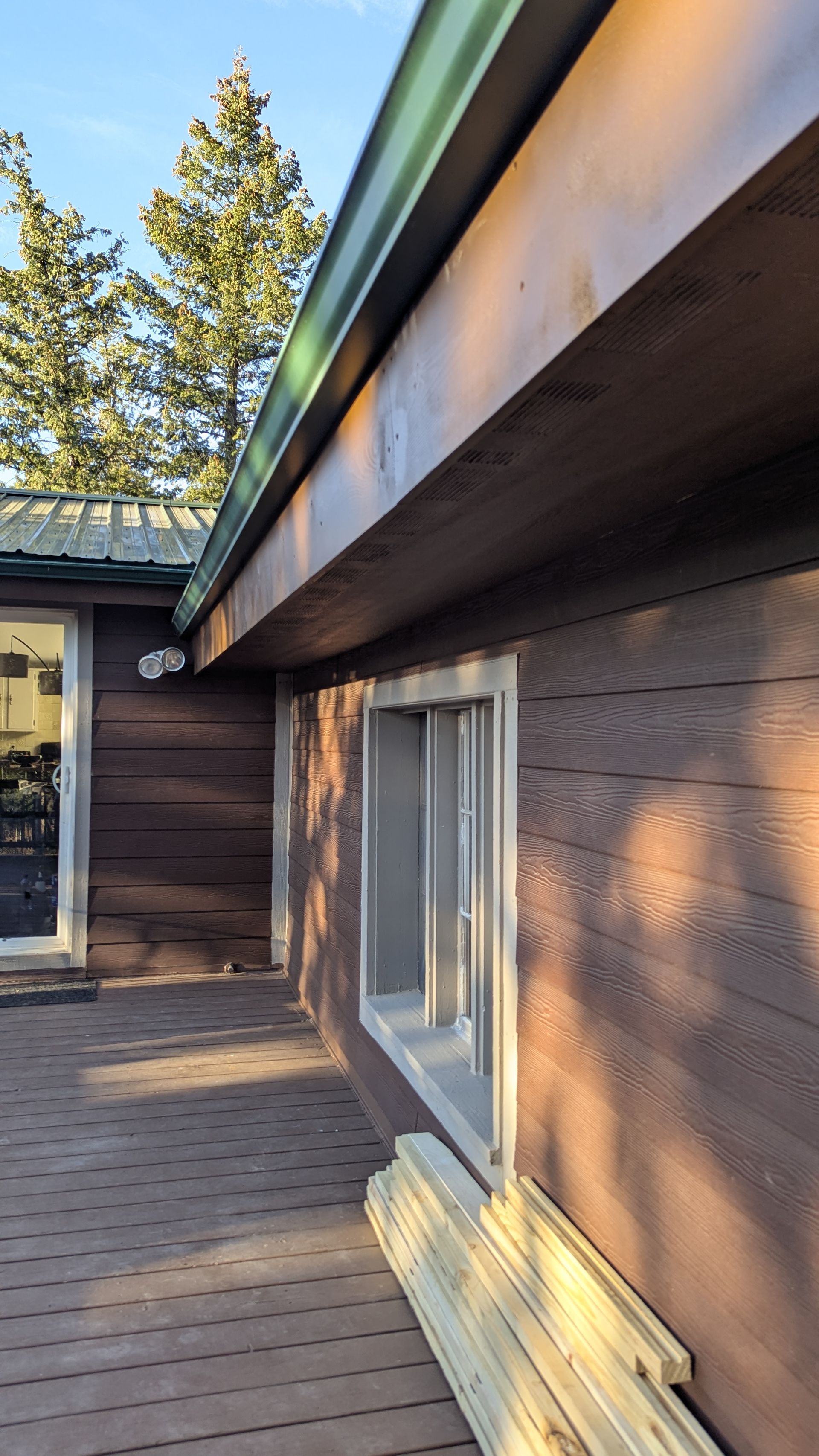 Brown building exterior with a window and green gutter.