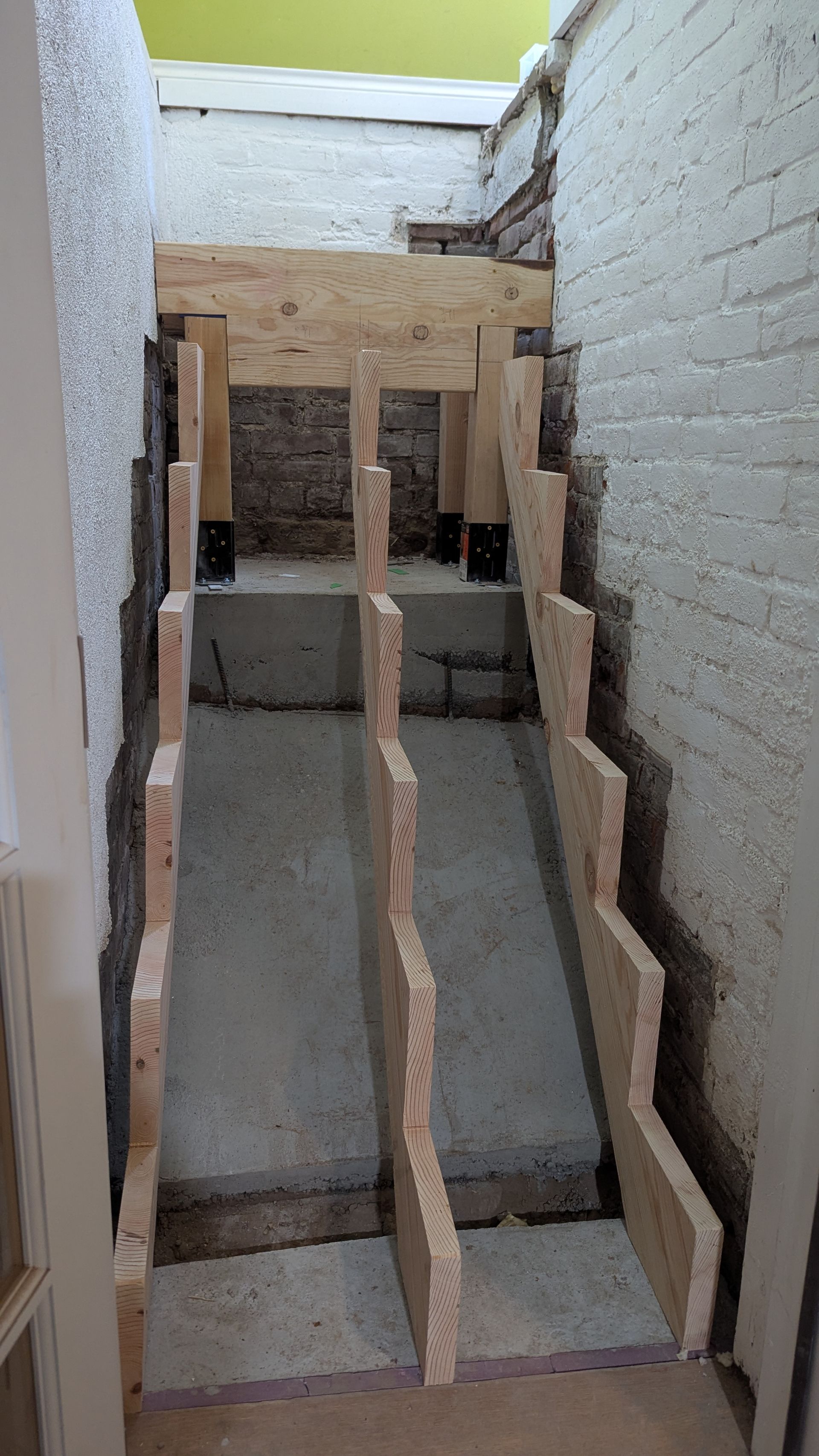Carpeted staircase with white walls, leading upwards. Person's legs visible at the top.