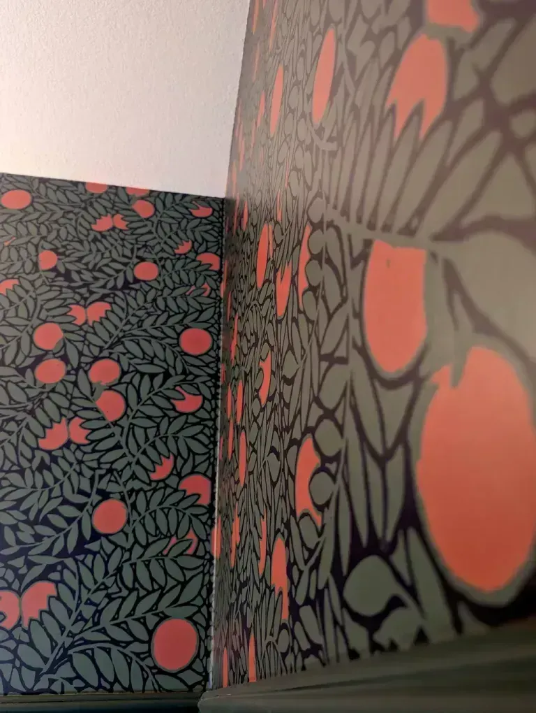 Wallpaper with a green and coral pattern of leaves and fruit.