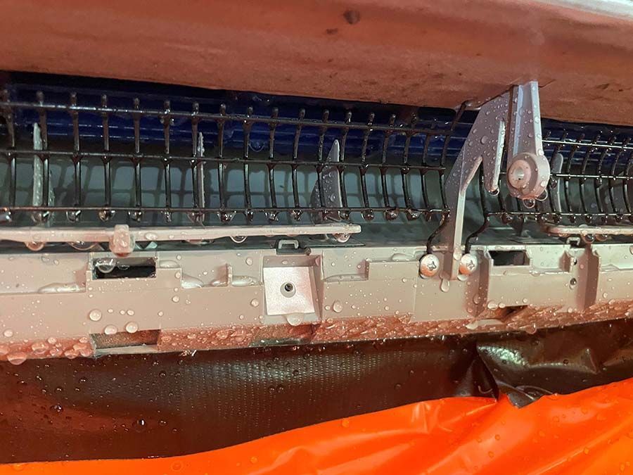 A close up of a dirty air conditioner sitting on top of an orange tarp.