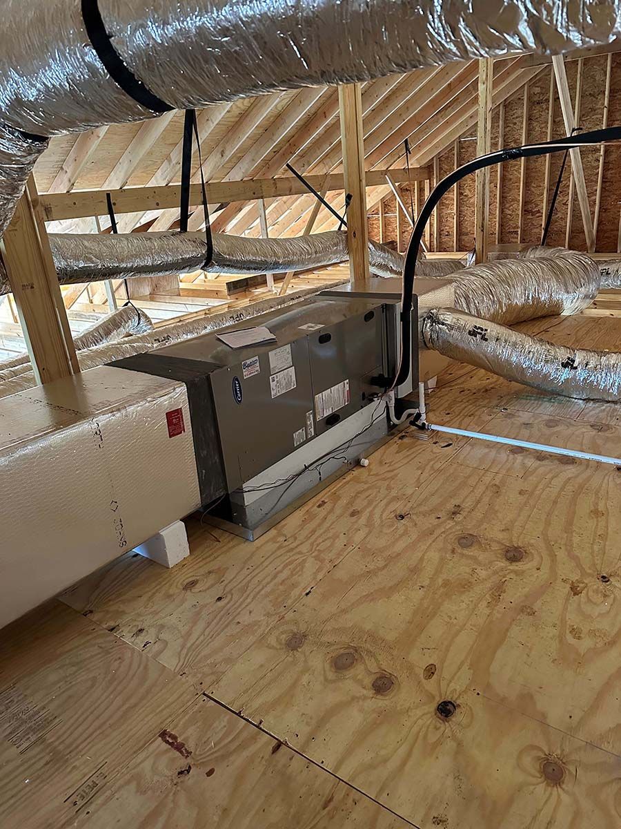 An air conditioner is sitting in the attic of a house under construction.