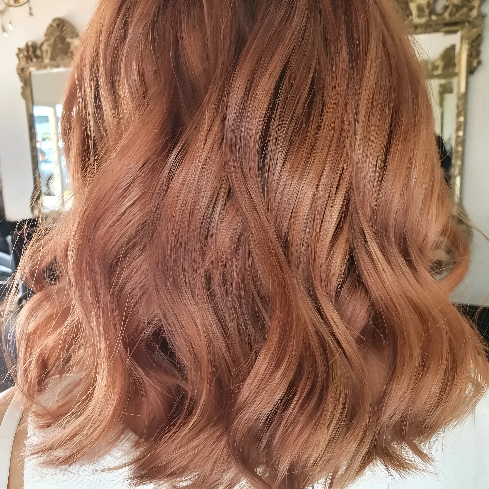Shoulder-length hair with loose waves, coloured in a warm, coppery-ginger shade, seen from the back.