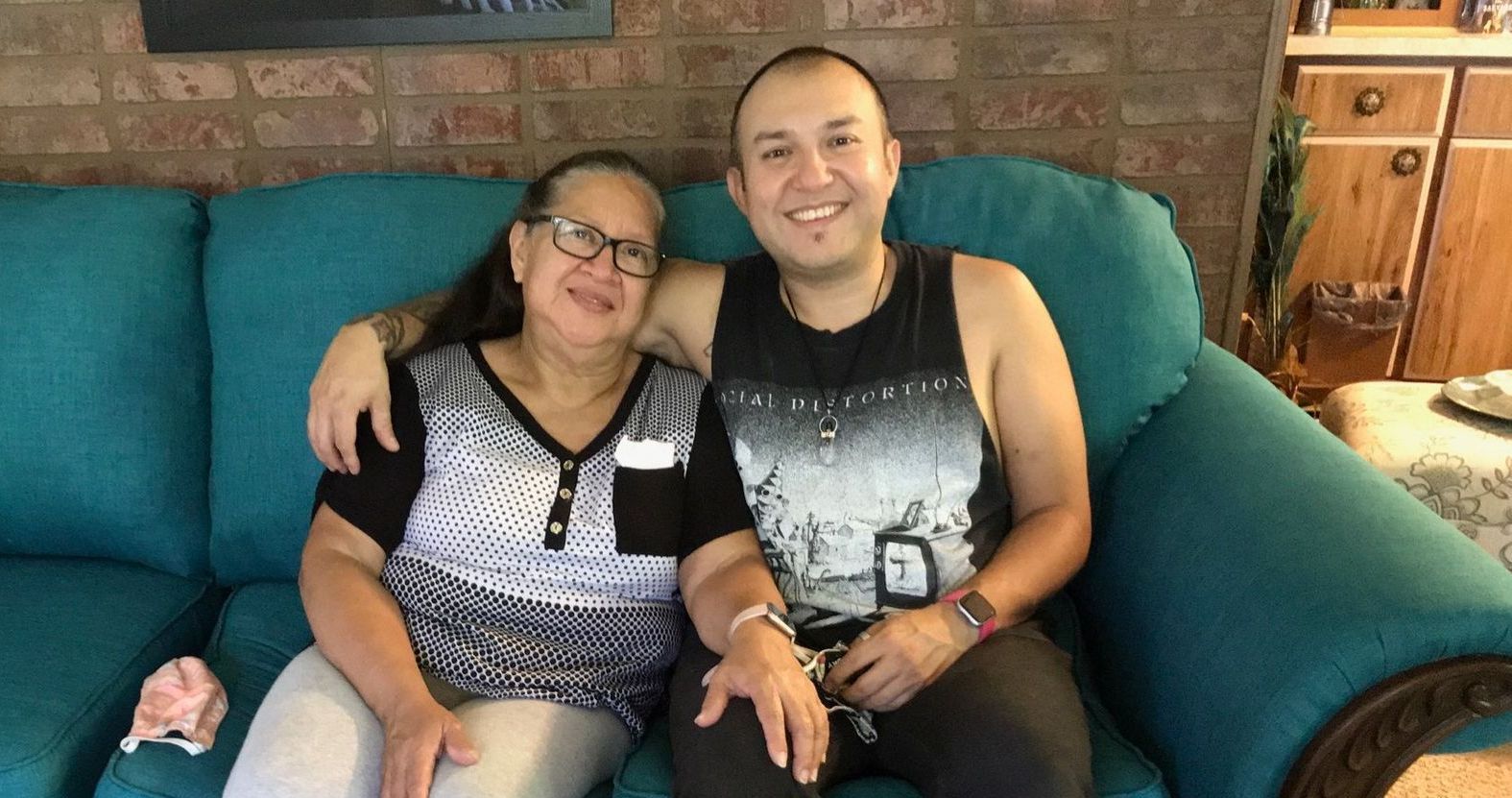 A man and a woman are sitting on a blue couch.