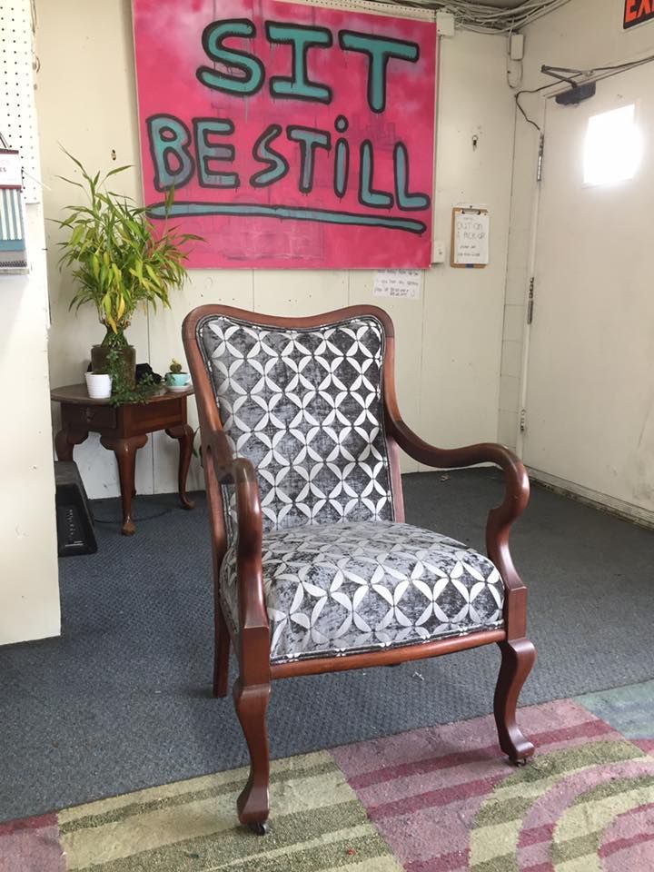 A chair is sitting in front of a sign that says sit be still
