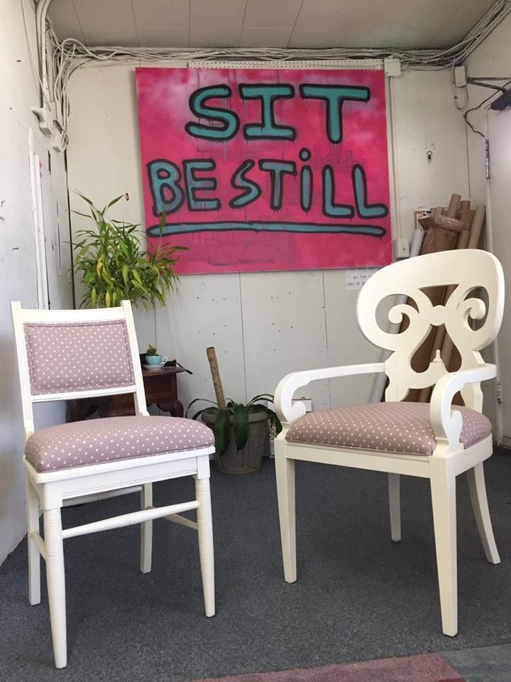 Two chairs in front of a sign that says sit be still