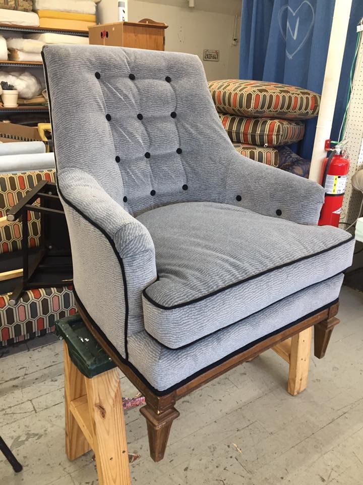 A grey chair is sitting on a wooden stool in a room.