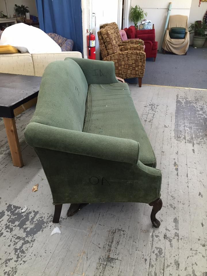 A green couch is sitting in a room with other furniture