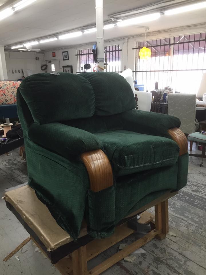 A green recliner is sitting on top of a wooden table in a room.