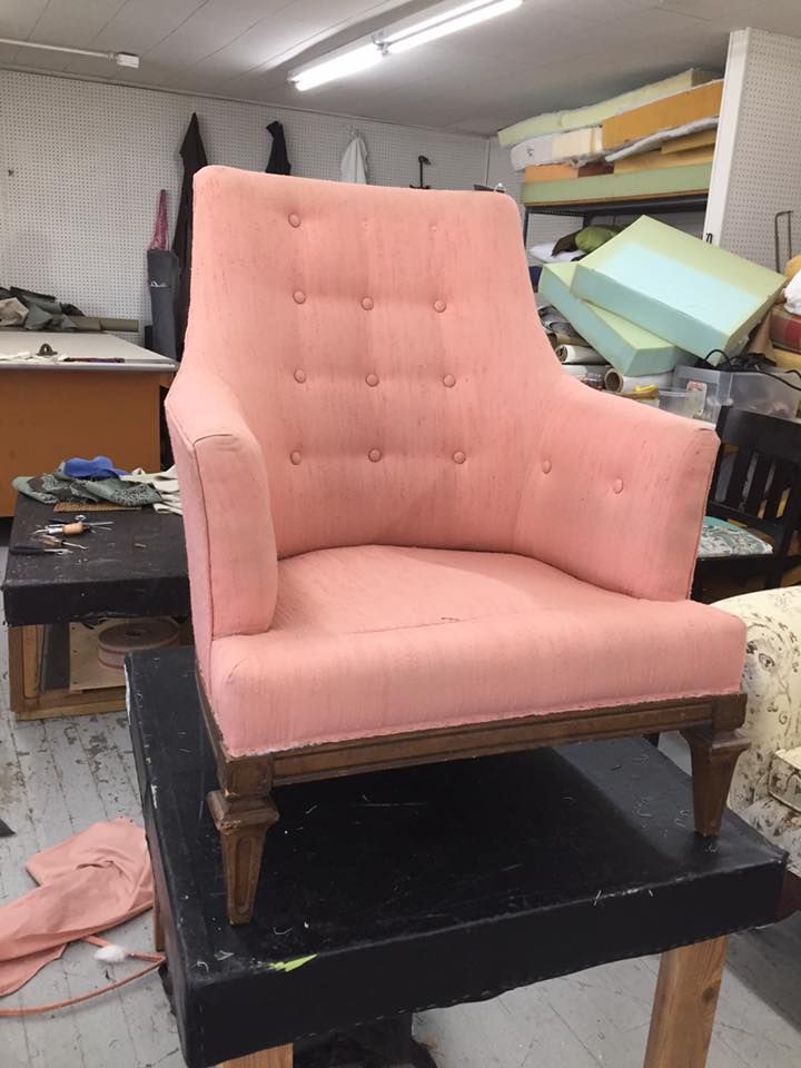 A pink chair is sitting on top of a table in a room.