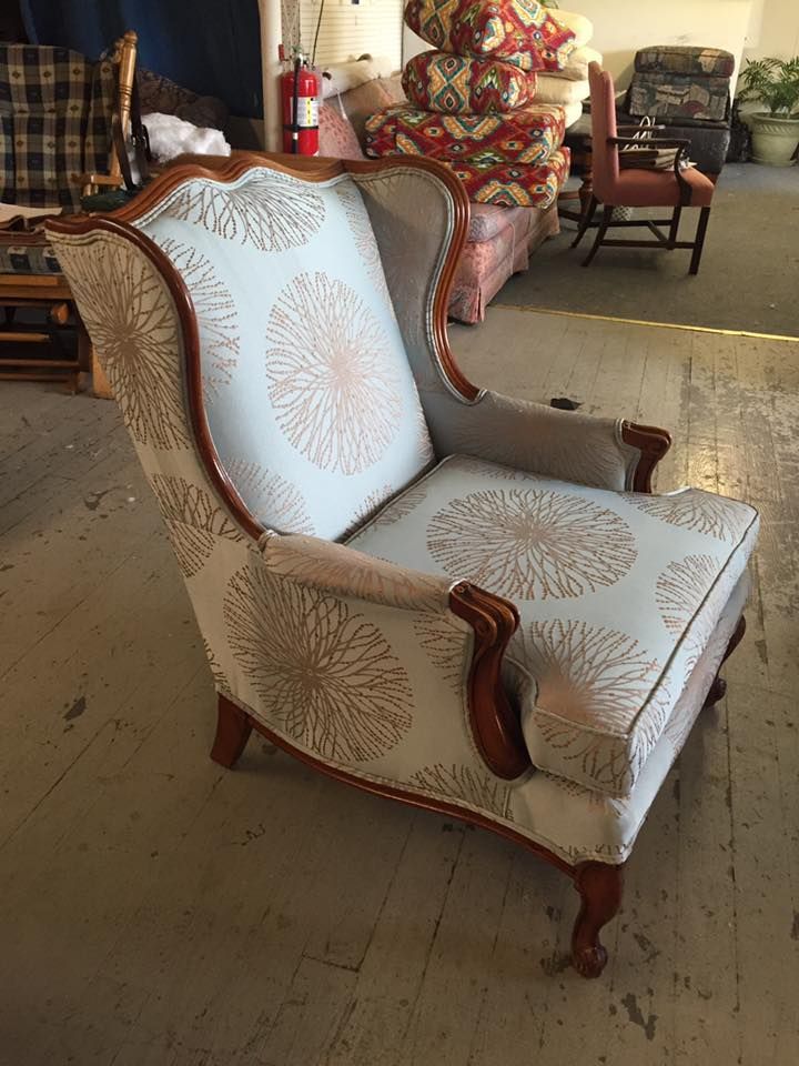 A chair with a pattern on it is sitting on a wooden floor in a room.