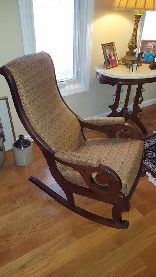 A rocking chair is sitting in a living room next to a table.