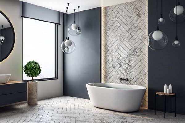 Salle de bain moderne avec baignoire, miroir rond et globes lumineux suspendus.