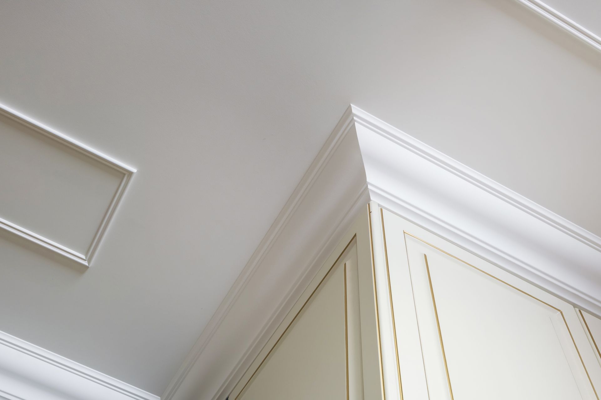 Moulure de couronne blanche et détail du plafond avec une armoire.