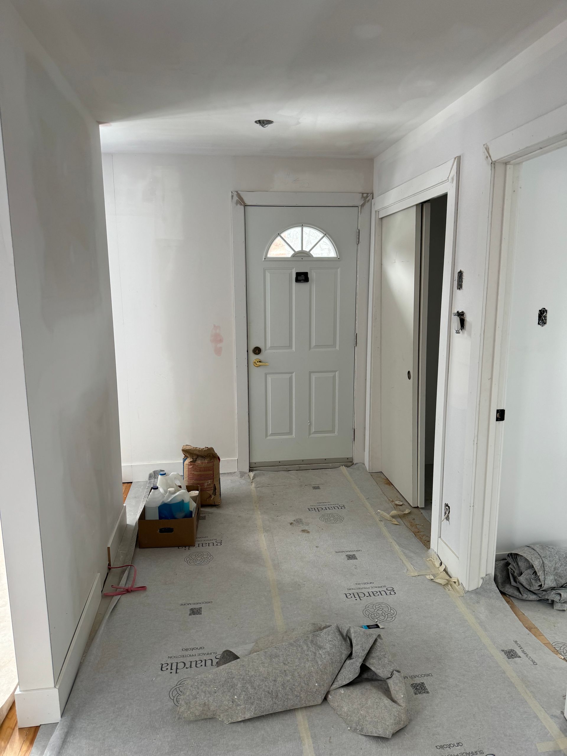 Couloir aux murs, à la porte et au sol blancs. Matériaux de construction au sol.