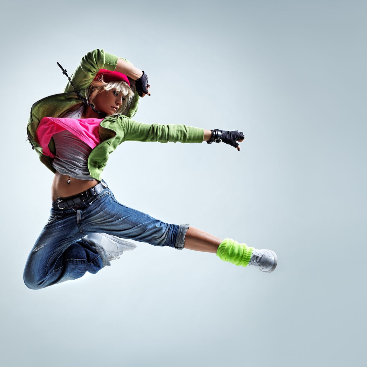 Ballerina a mezz'aria, indossa una giacca verde, una maglietta rosa e jeans. 