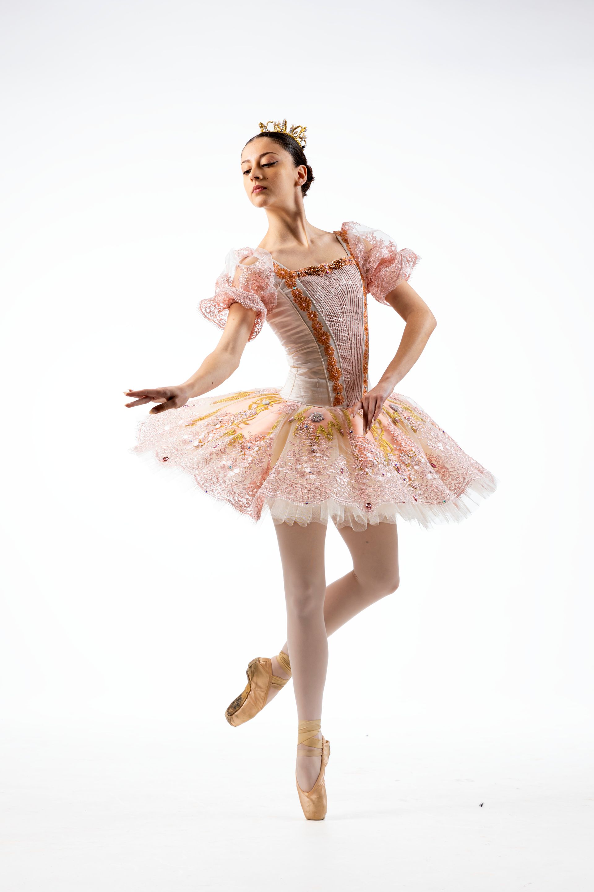 Ballerina in spaccata a mezz'aria, braccia alzate, indossa un abito blu e scarpe da punta.