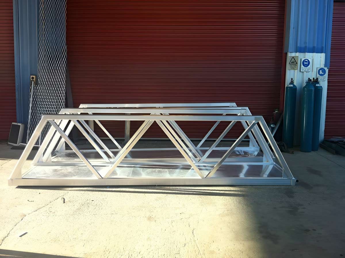 The Aluminum Structure Is Sitting In Front Of A Red Garage Door — Brumb's Welding & Fabrication in Biggera Waters, QLD