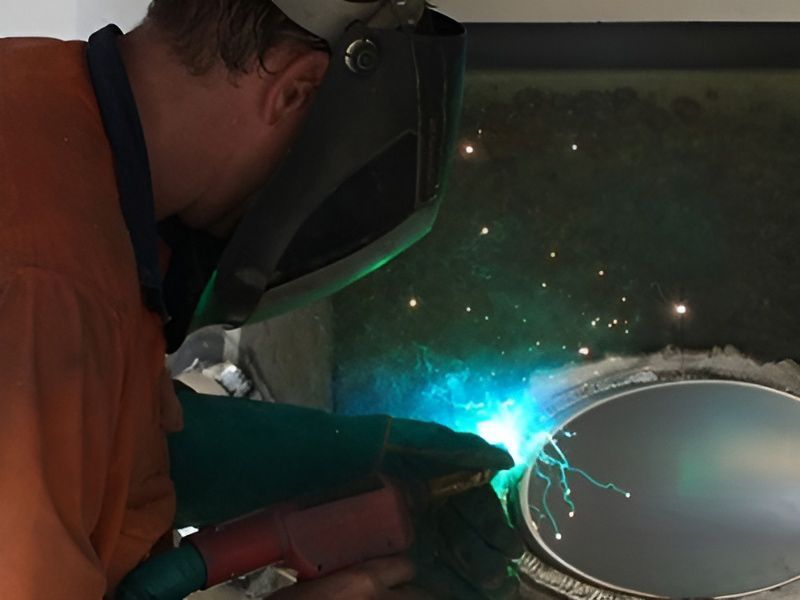 A Man Wearing A Welding Mask Is Welding A Piece Of Metal — Brumb's Welding & Fabrication in Biggera Waters, QLD