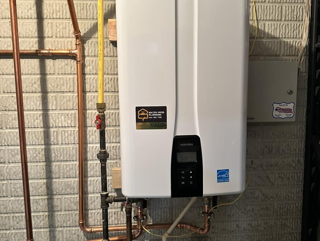 White tankless water heater on a brick wall with copper pipes and a yellow gas line.