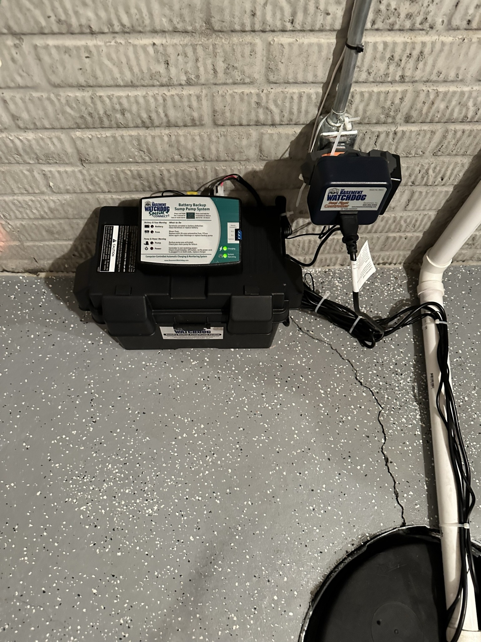 Black box containing irrigation control system attached to a brick wall.