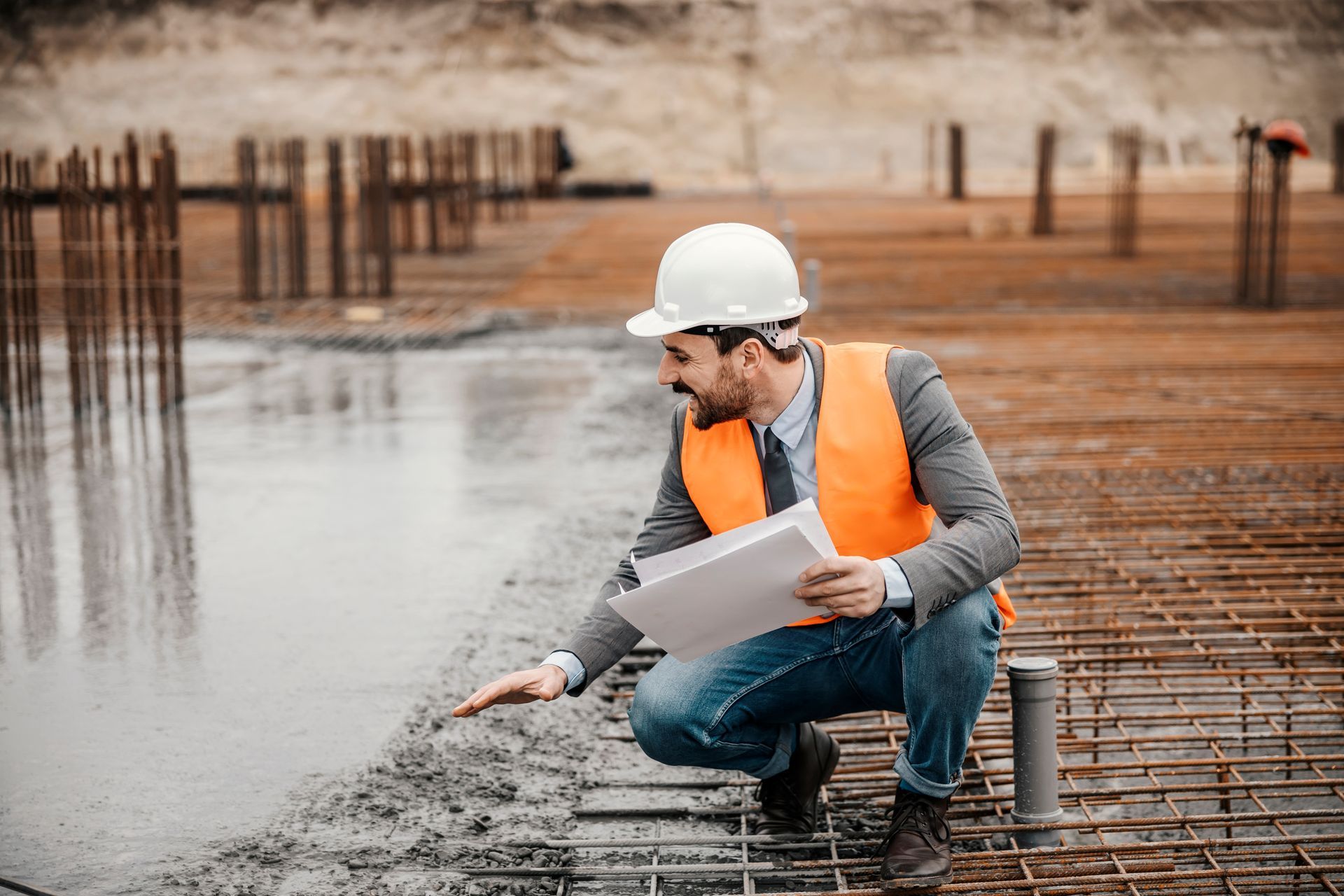 a construction worker is kneeling down on a construction site looking at a blueprint .