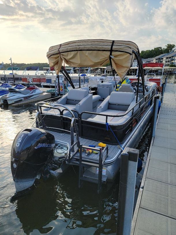 Dirty Duck Boat Rentals | Lake of the Ozarks a pontoon boat with a canopy is docked at a dock .