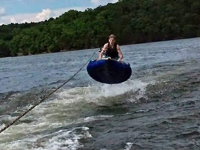 Dirty Duck Boat Rentals | Lake of the Ozarks a person is riding a tube on a lake .