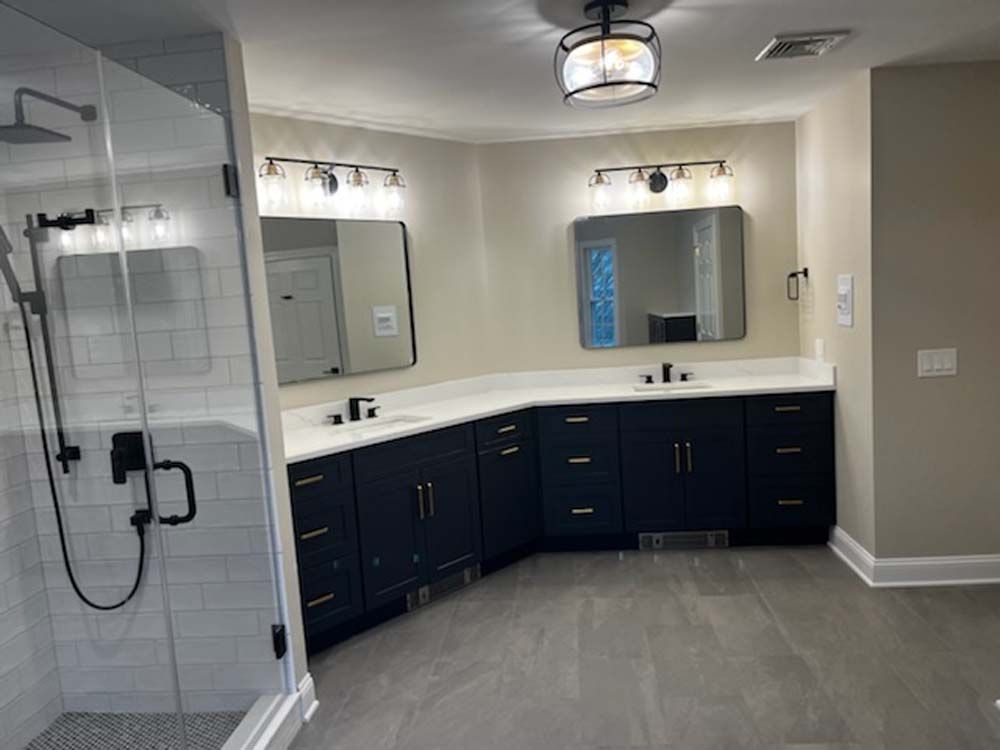 A bathroom with two sinks , a shower and a mirror.