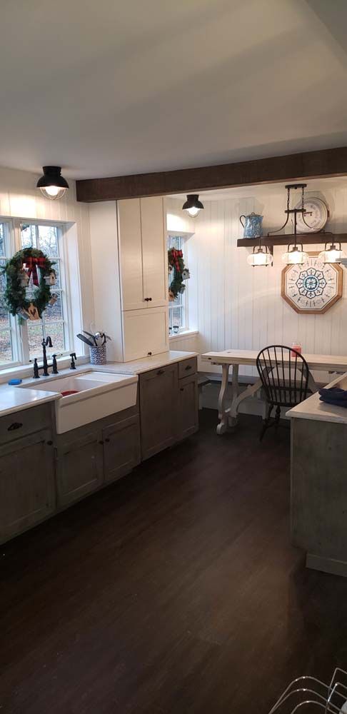 A kitchen with a sink , table , chairs and a clock on the wall.