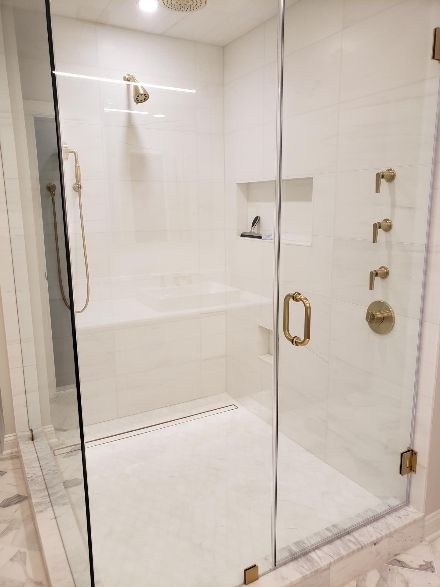 A bathroom with a walk in shower with a glass door.