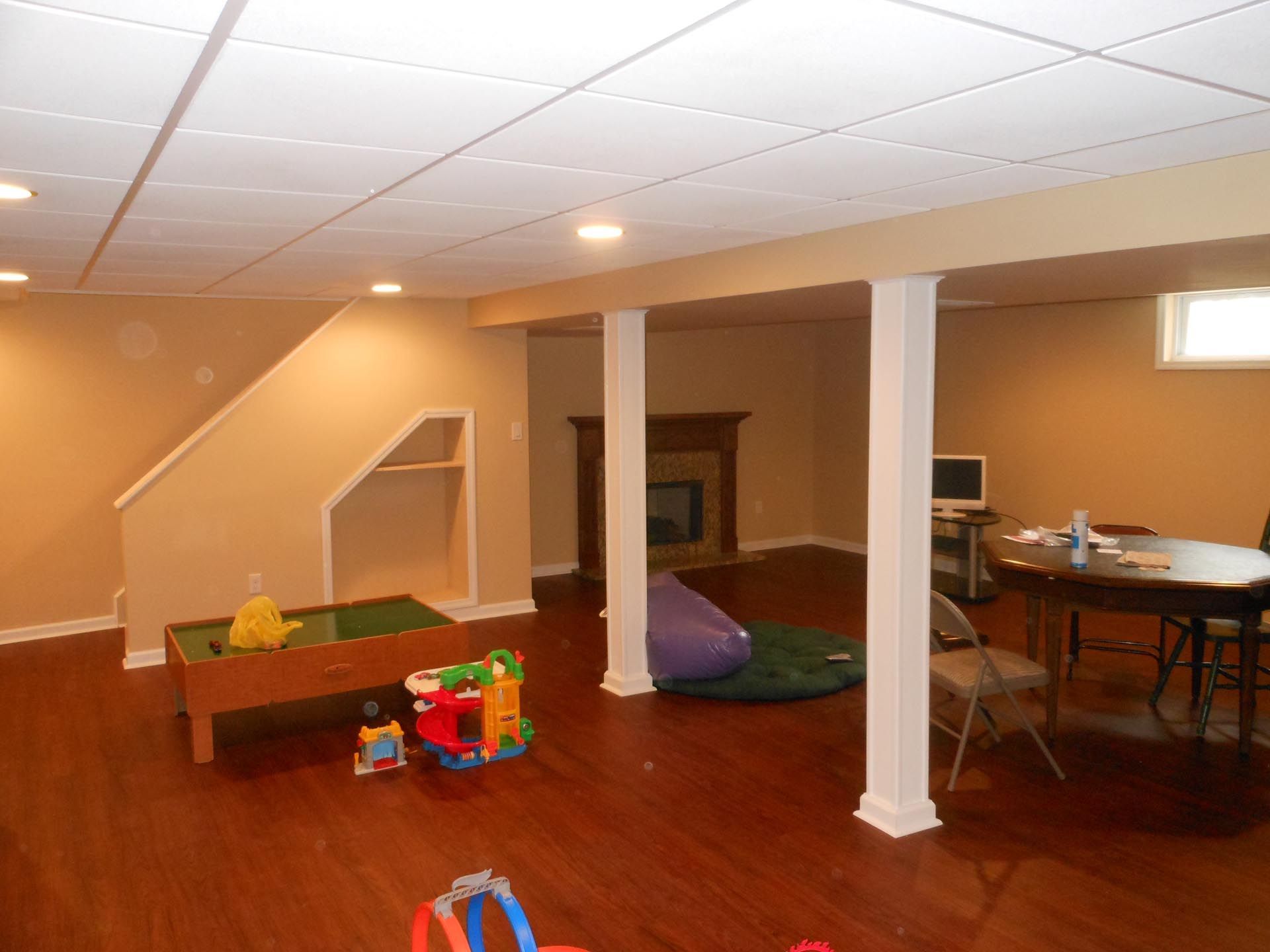 A basement with a table , chairs , and a fireplace.