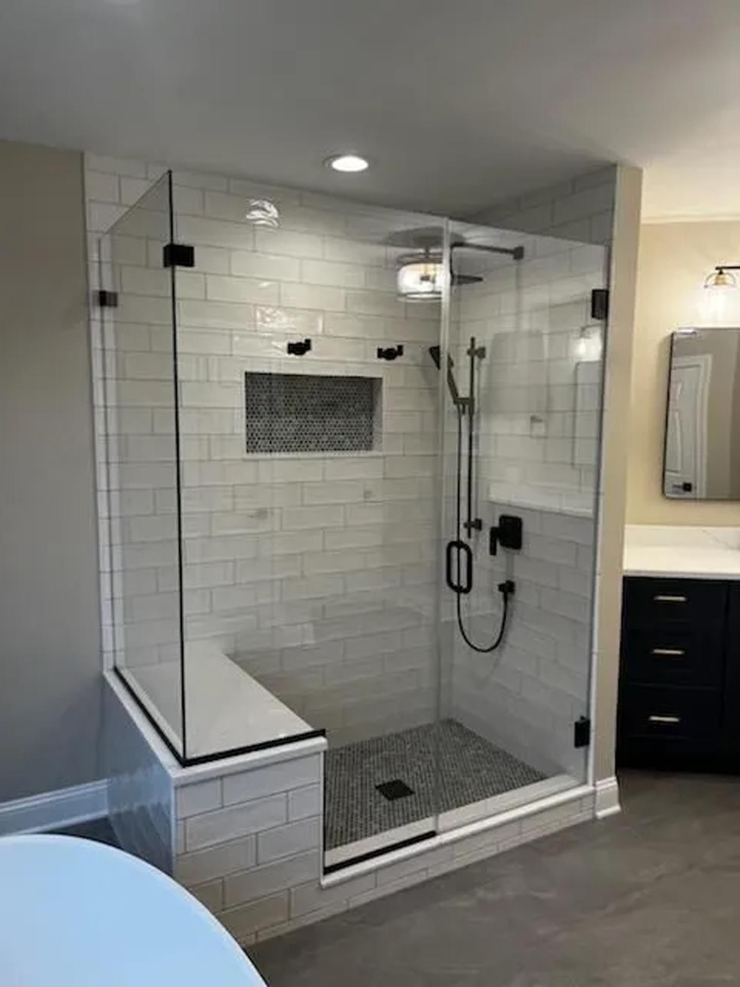 A bathroom with a walk in shower with a glass door.