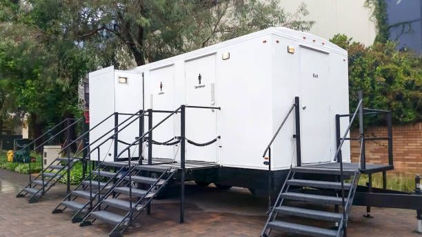 A white trailer with stairs attached to it is parked in front of a building.