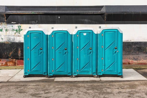 Four aqua-colored mobile toilet units.