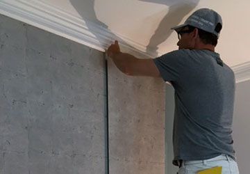 Un homme mesure un mur avec un ruban à mesurer.