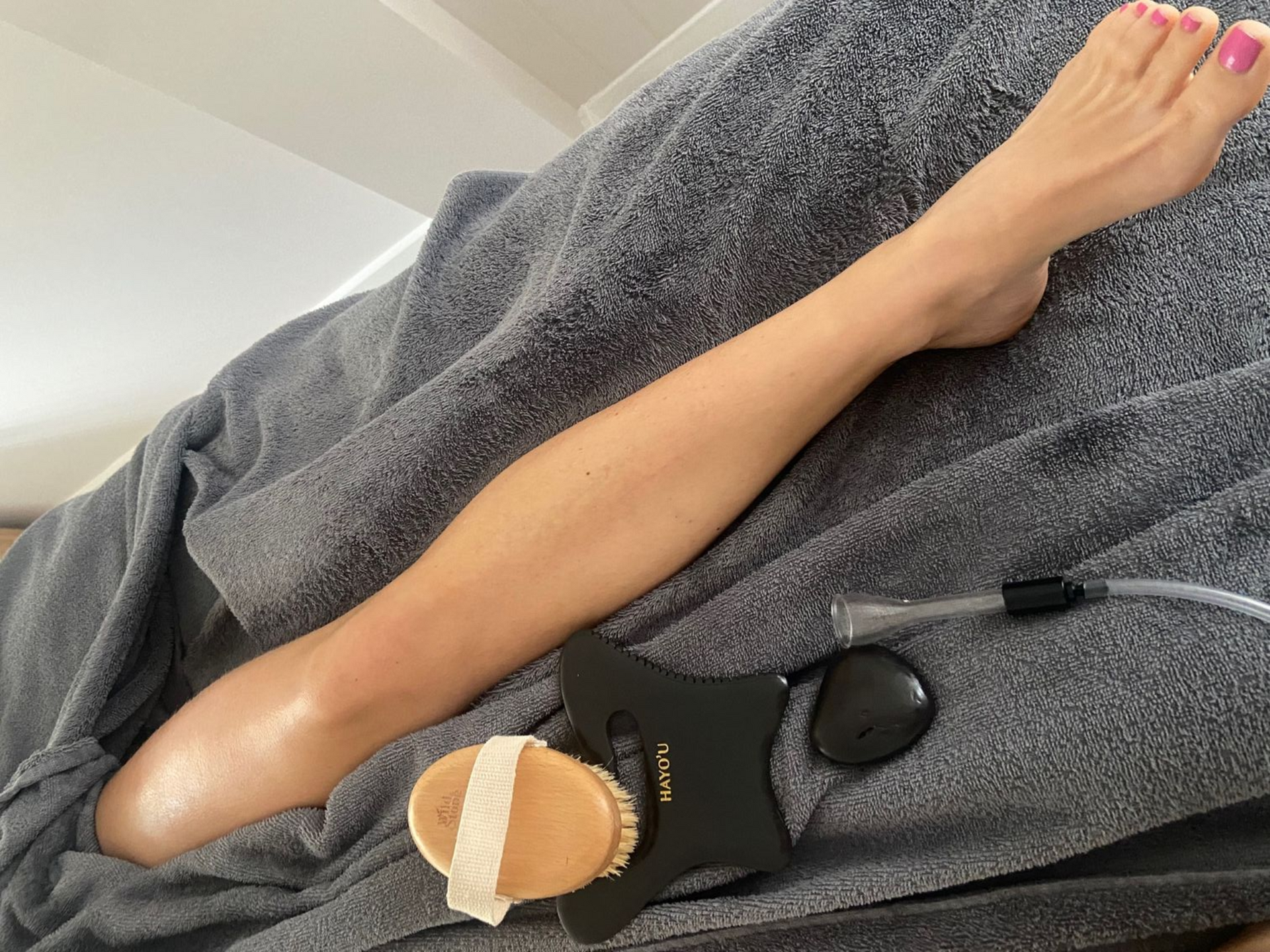 Leg on gray towel with massage tools.