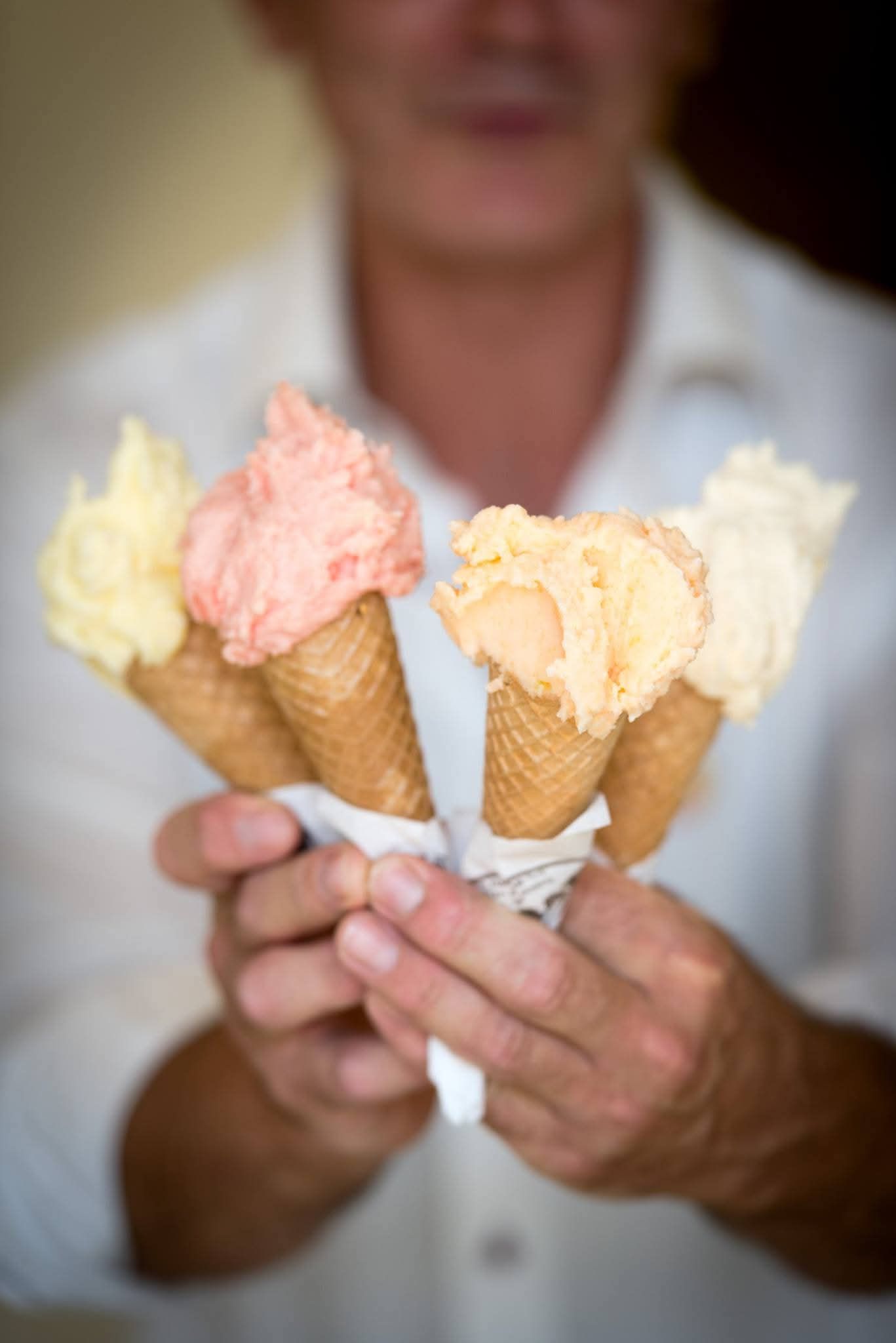 Un uomo tiene in mano quattro coni gelato.