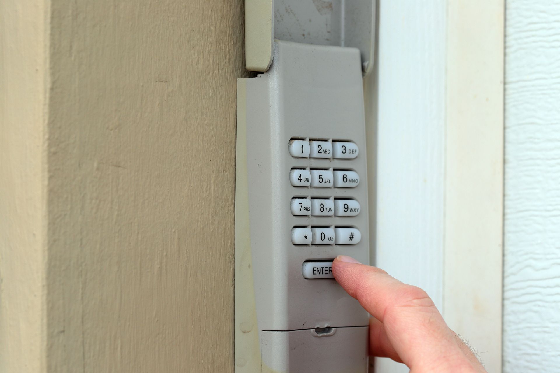 A person is pressing a keypad on a wall.