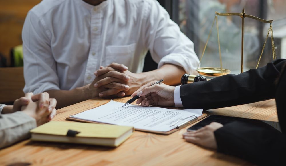 A group of people are sitting at a table having a meeting with a lawyer.
